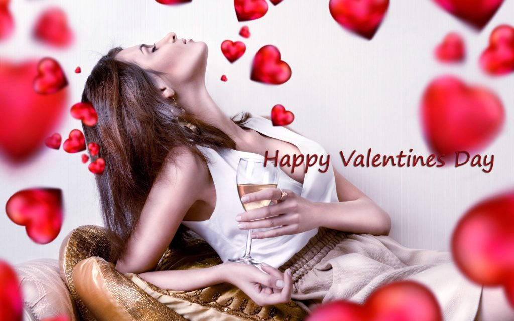 Happy Valentines Day 桌布 壁紙 — 一位女士躺在一張金色沙發上，手持酒杯，紅色愛心在她周圍飄浮，慶祝情人節。
