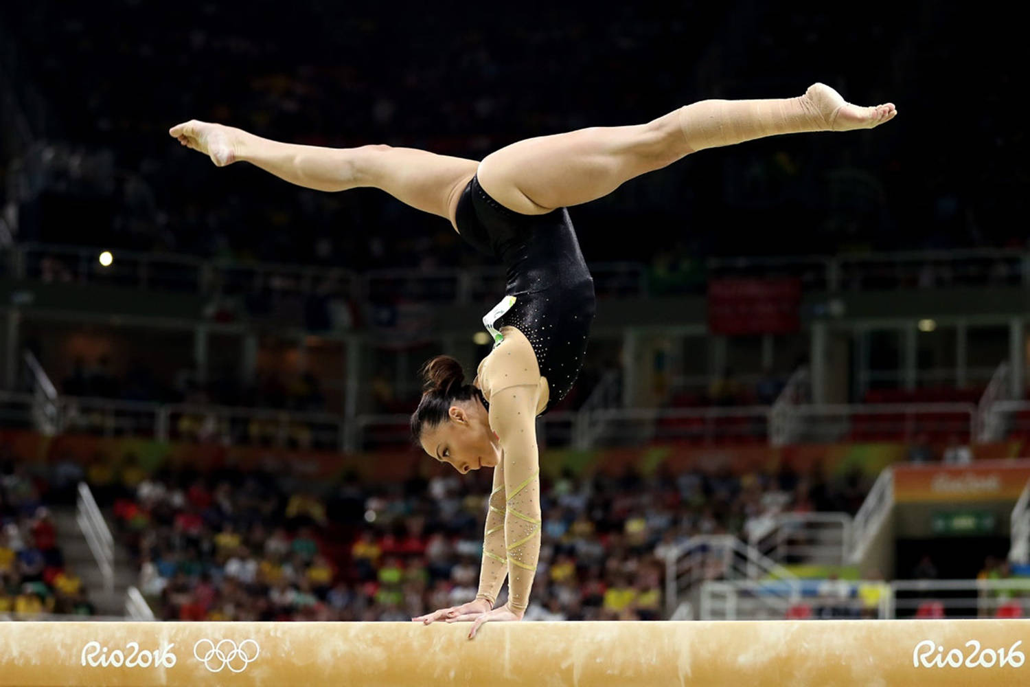 Olympics 桌布 壁紙 — 一位女子體操運動員在里約2016奧運會明亮的場館燈光下，在平衡木上精準地執行倒立動作。