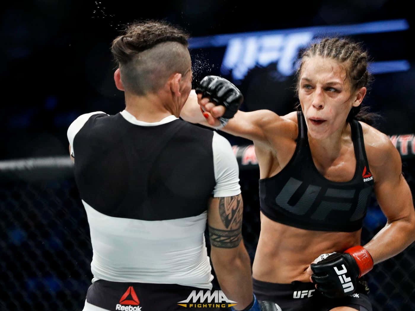professional 桌布 壁紙 — 一位女性MMA拳手在明亮的場館燈光下，於UFC八角籠中對對手打出強力一拳。