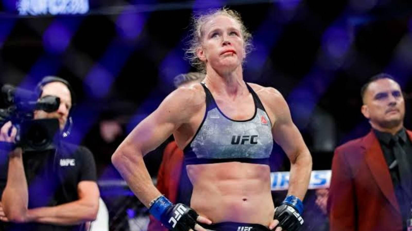 MMA 桌布 壁紙 — 一位女性UFC拳手在八角籠中勝利站立，在明亮的場館燈光下展現勝利表情。