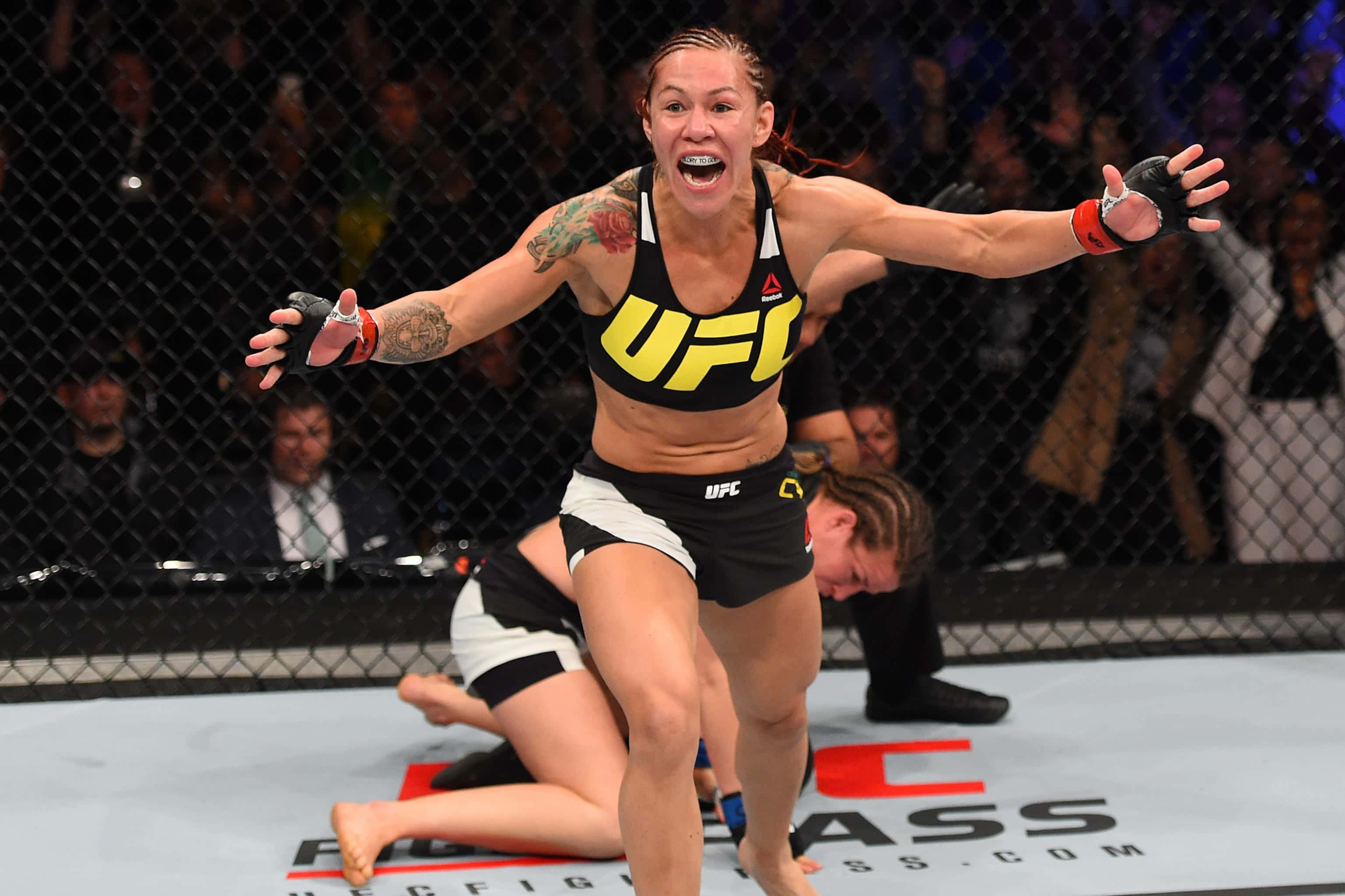 UFC 桌布 壁紙 — 一位女性UFC拳手在八角籠中張開雙臂，發出勝利的吶喊慶祝勝利。