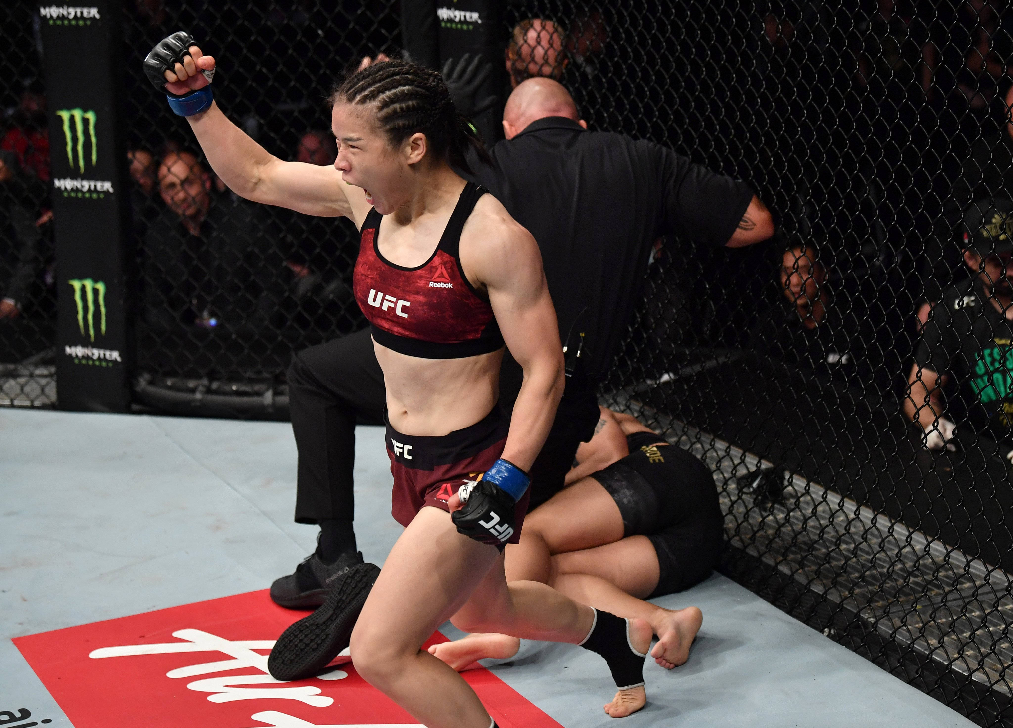 Champion 桌布 壁紙 — 一位女性UFC拳手在八角籠內裁判停止比賽時，勝利地高舉拳頭。
