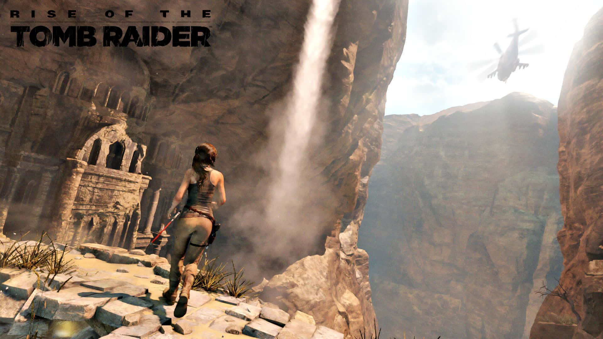 Lara Croft 桌布 壁紙 — 一位女性冒險家在古老廢墟附近的岩石懸崖上奔跑，背景有瀑布和直升機。