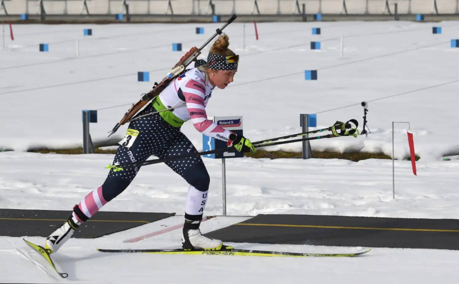 運動 桌布 壁紙 — 一位女性冬季兩項運動員在雪地中滑雪前進，步槍掛在肩上。