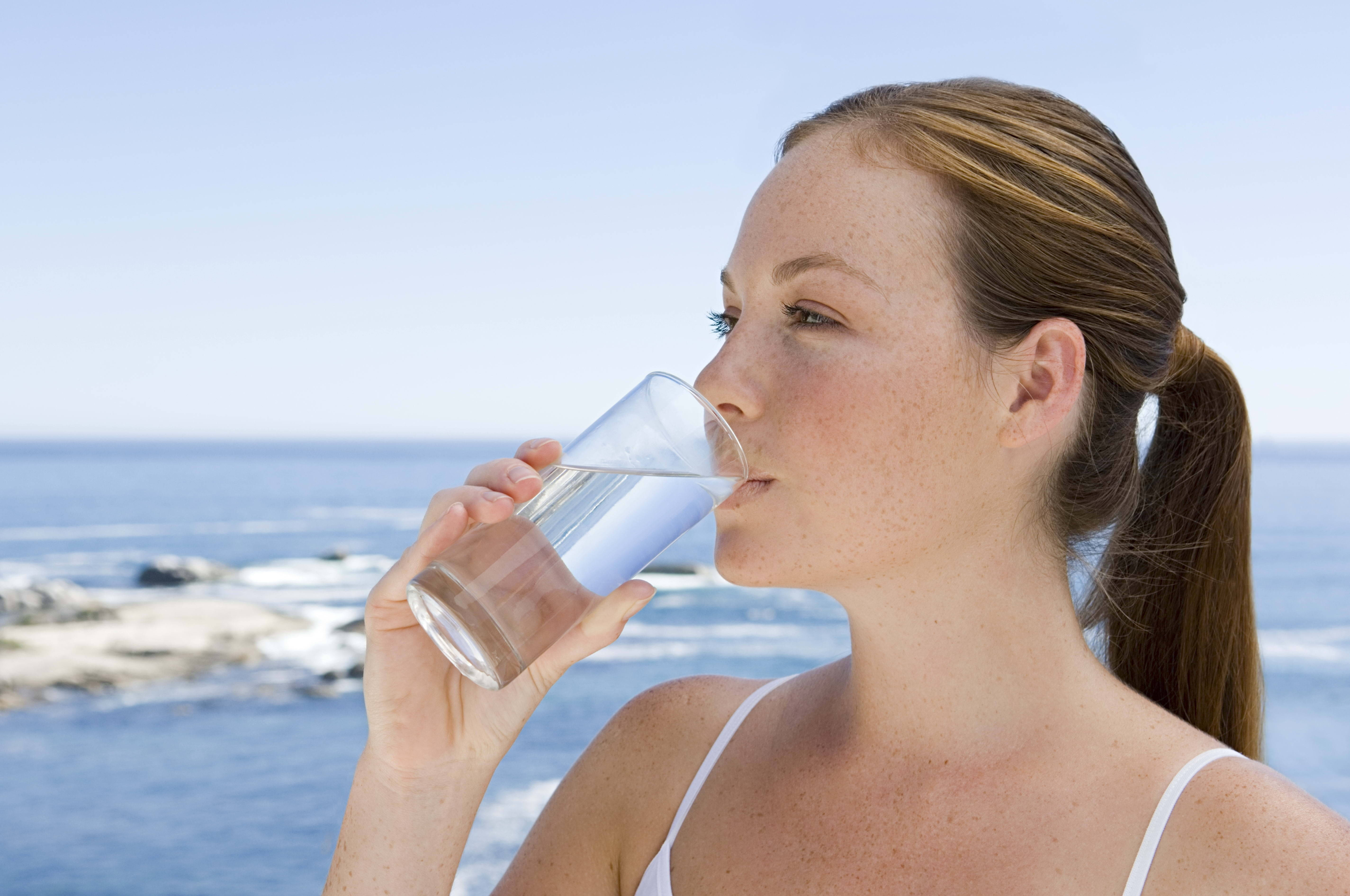 Drinking 桌布 壁紙 — 一位女性在明亮的海岸背景下，以海洋和天空為襯托，從玻璃杯啜飲水。