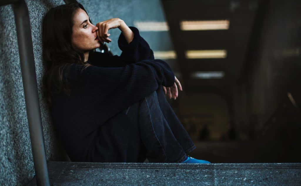 一位女性坐在空蕩走廊的樓梯上 壁紙