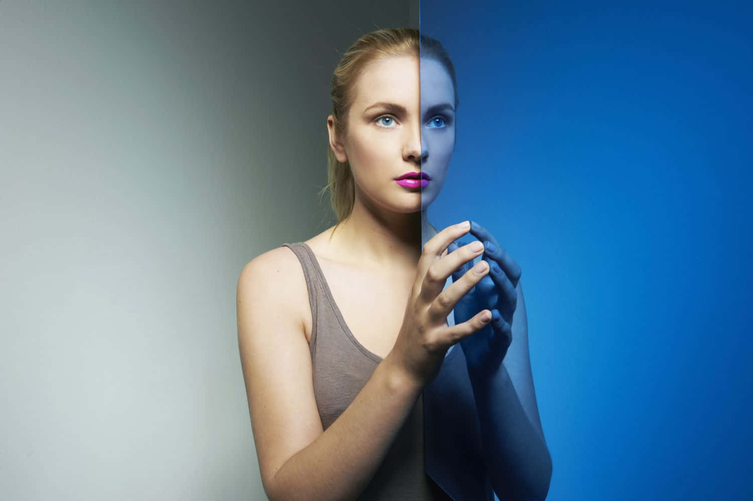 reflection 桌布 壁紙 — 一位女性從中間分開，一側處於中性光線，另一側處於鮮豔的藍色，雙手在胸前交握。