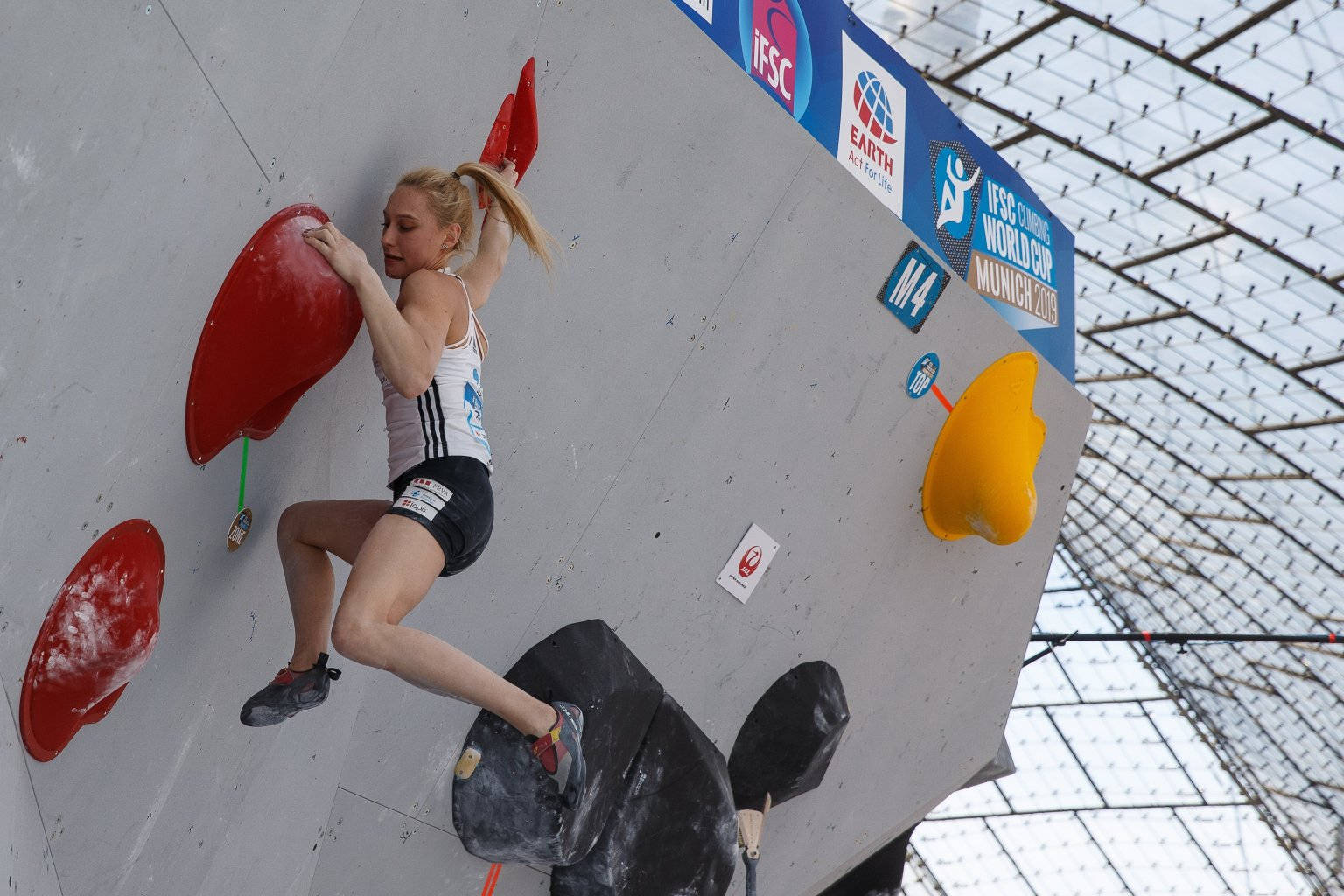 Climbing 桌布 壁紙 — 一位女性攀岩者在IFSC世界盃賽事中，專注地攀爬陡峭的室內抱石牆。