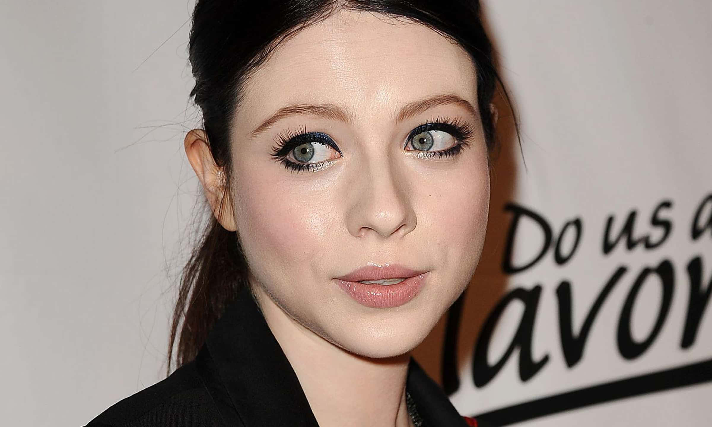 michelle trachtenberg 桌布 壁紙 — 一位女性的特寫肖像，她有搶眼的藍色眼睛和大膽的眼線，背景是純白色。