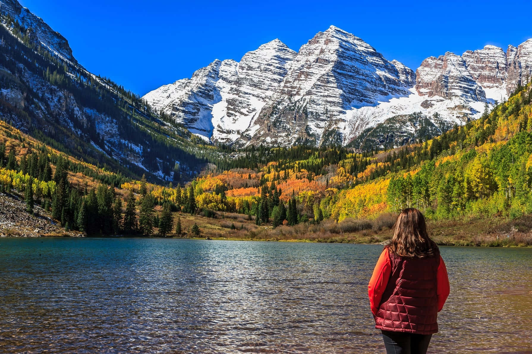一位女性站在湖前，背景是群山 壁紙