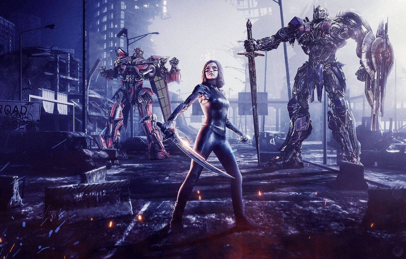 Alita 桌布 壁紙 — 一位女戰士揮舞著發光的劍，旁邊是兩座高聳的變形金剛，在廢墟城市景觀中，天空籠罩著朦朧的暮色。