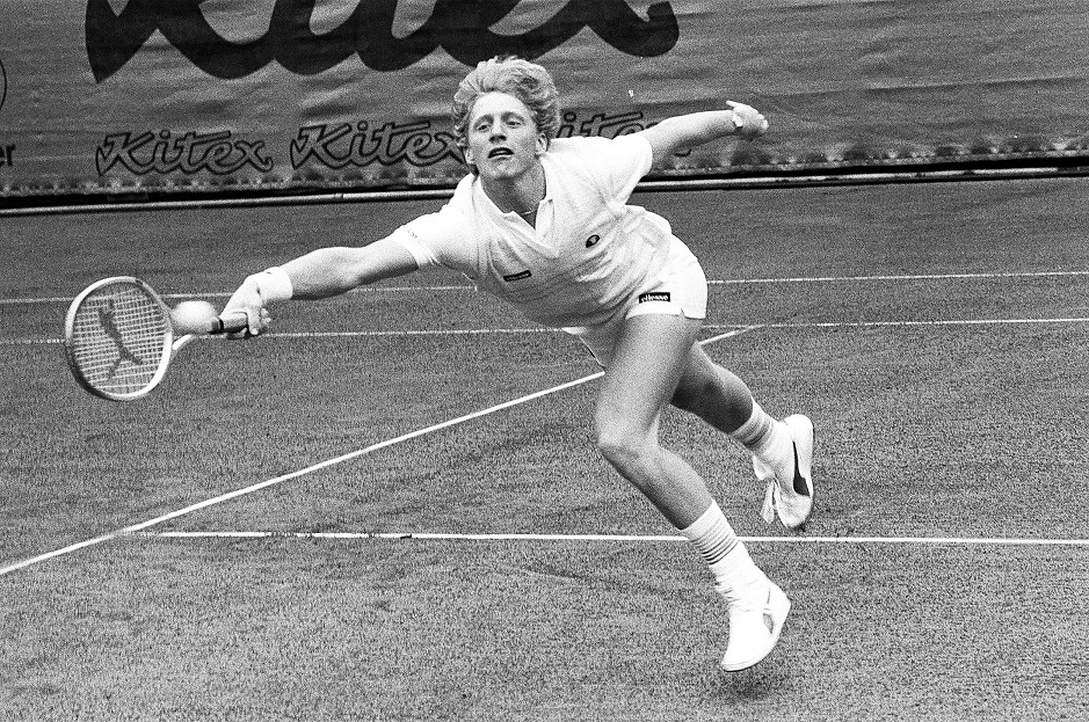 Boris Becker 桌布 壁紙 — 一位女網球運動員在草地場上動態地撲球，這張復古黑白照片捕捉了激烈的動作。