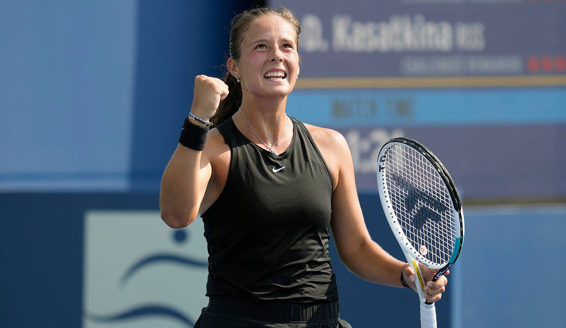 Athletic 桌布 壁紙 — 一位女網球運動員在藍色球場上握緊拳頭，帶著勝利的表情慶祝勝利。