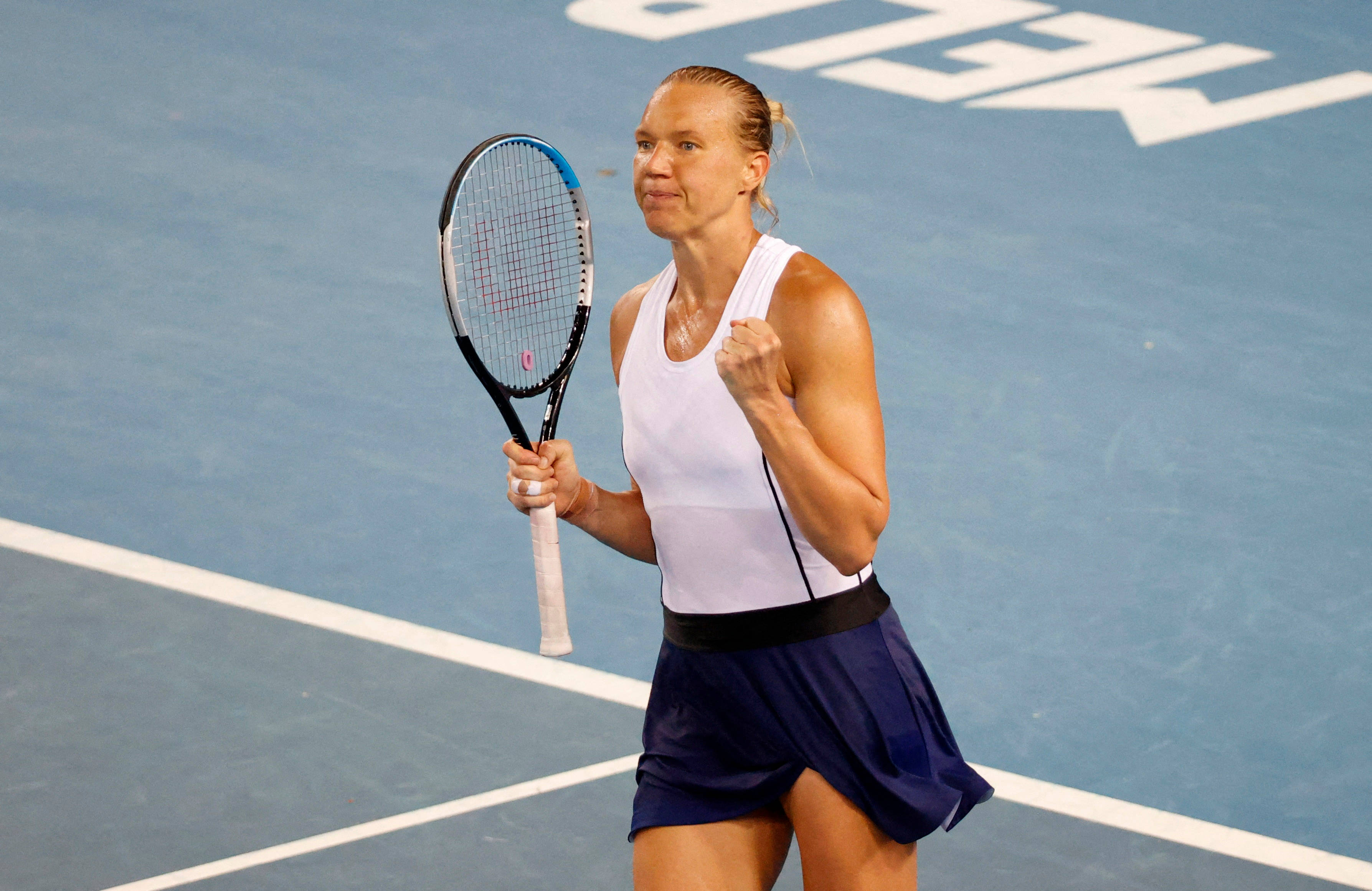 Tennis 桌布 壁紙 — 一位女網球運動員在藍色硬地球場上握緊拳頭並手持球拍慶祝勝利。