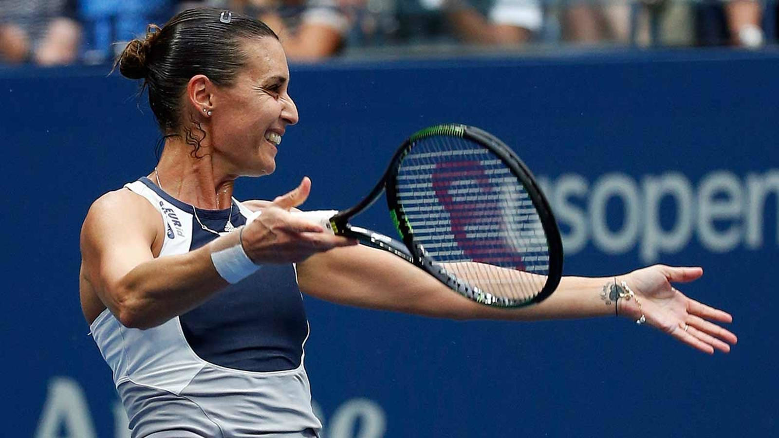 運動 桌布 壁紙 — 一位女網球運動員在藍色美國網球公開賽背景下揮拍時露出燦爛笑容。