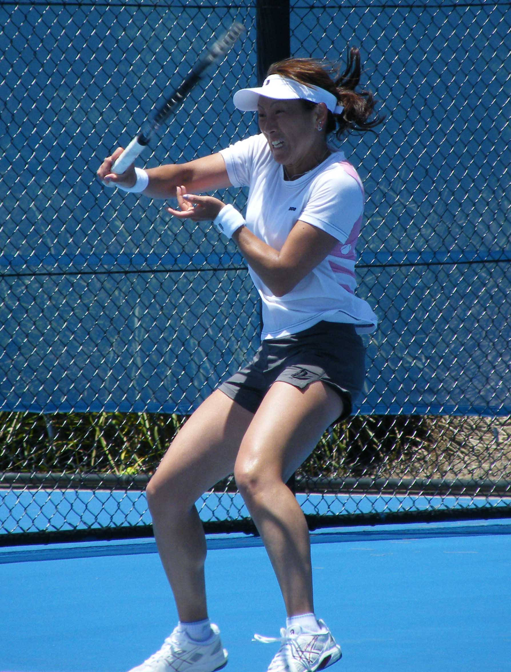 Athlete 桌布 壁紙 — 一位女網球選手在明亮的藍色球場上，在清晰日光下揮拍中。