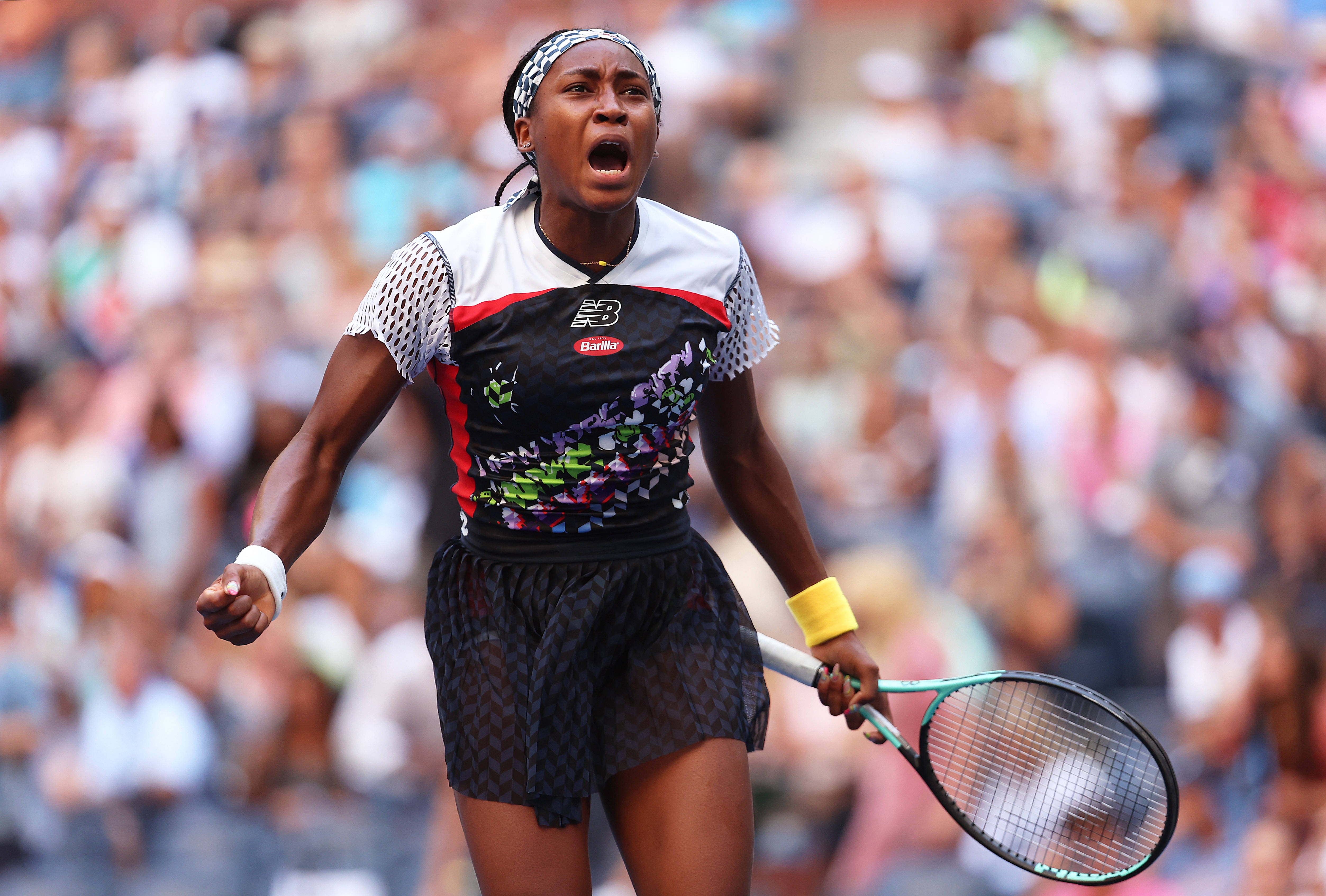 Coco Gauff 桌布 壁紙 — 一位女網球選手在比賽中高舉球拍，身後模糊的人群中發出勝利的吼叫。