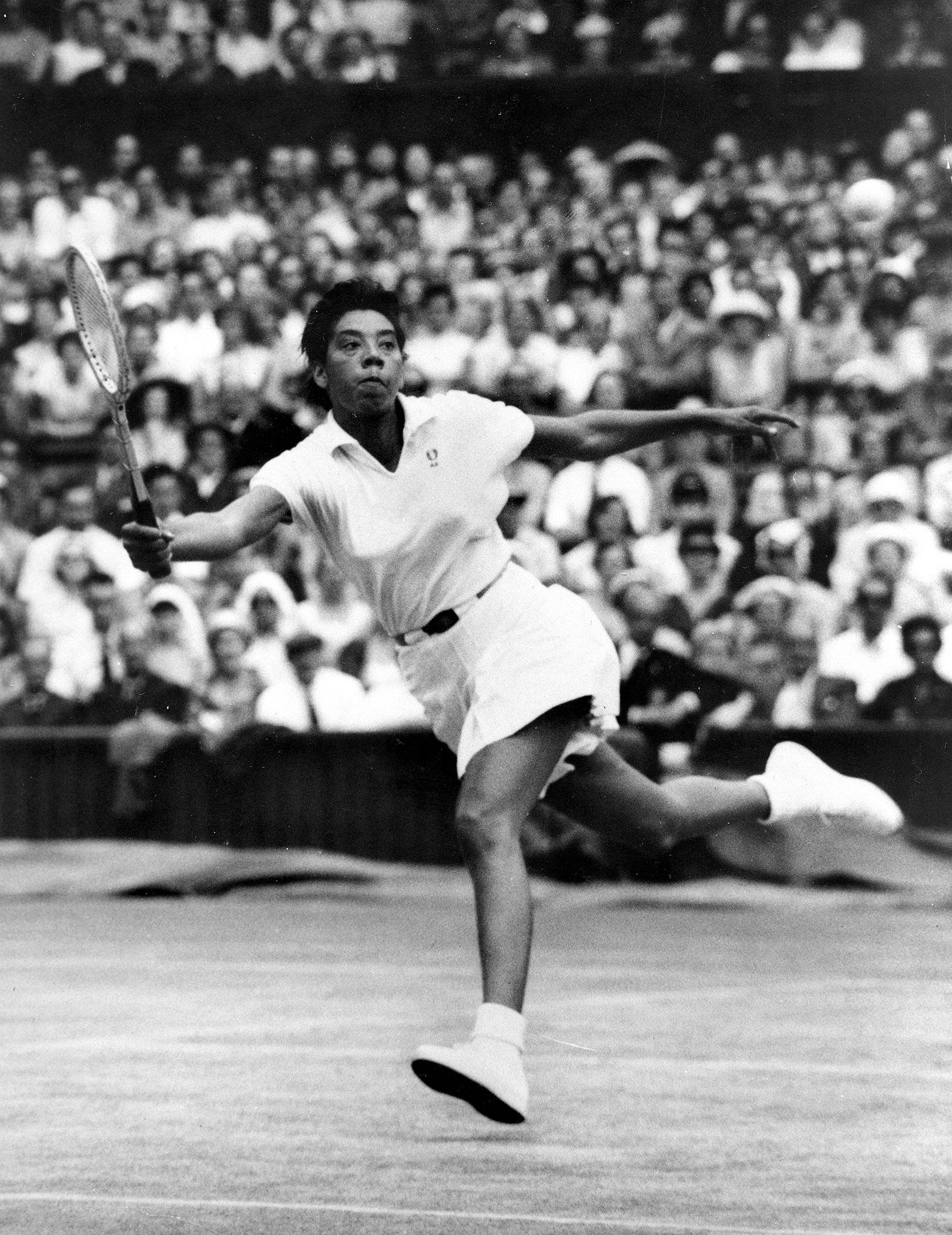 Tennis 桌布 壁紙 — 一位女網球選手在球場上揮拍中，背景有模糊的人群。