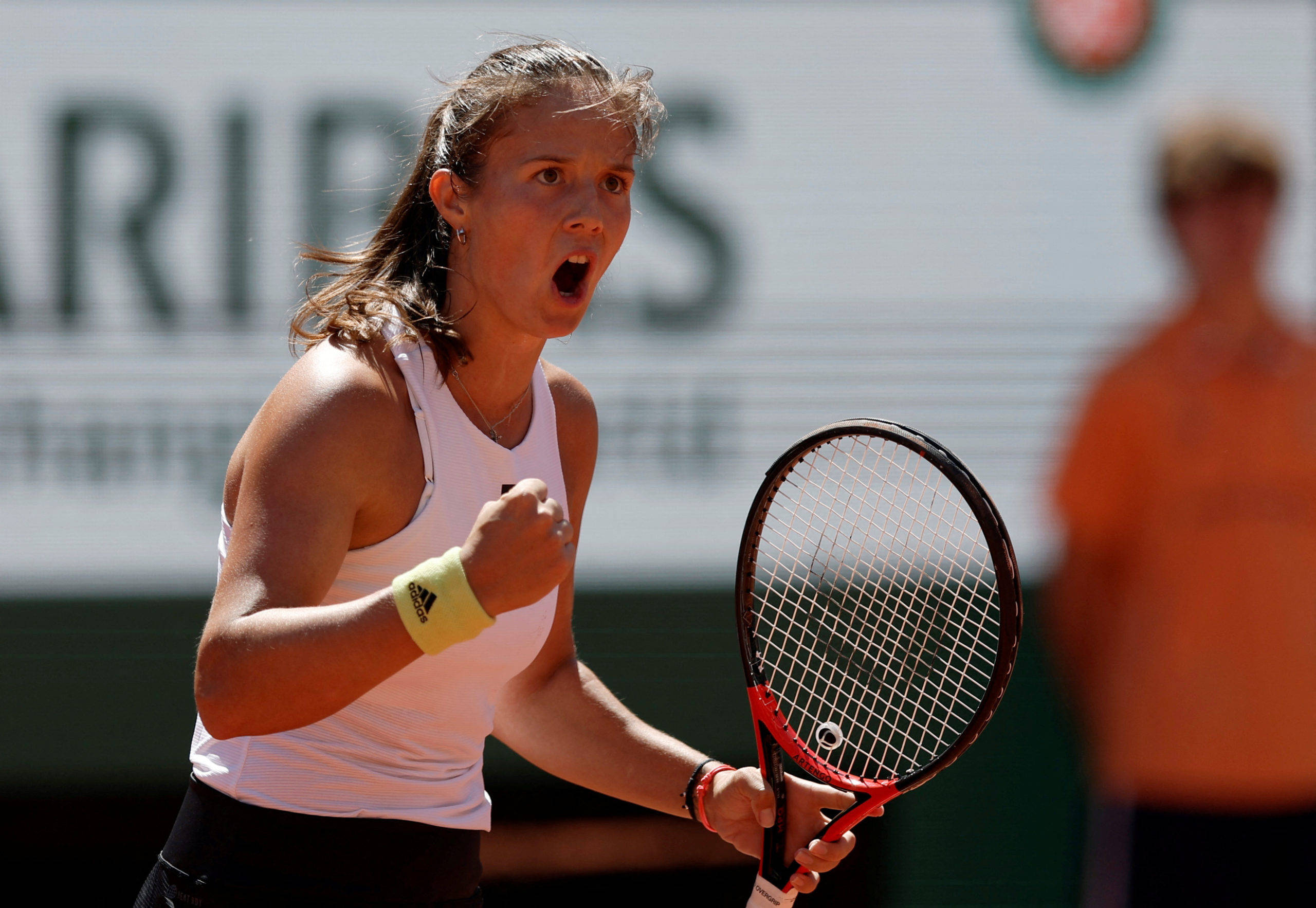 Athletic 桌布 壁紙 — 一位女網球選手在紅土球場上握緊拳頭、手持球拍熱情慶祝。