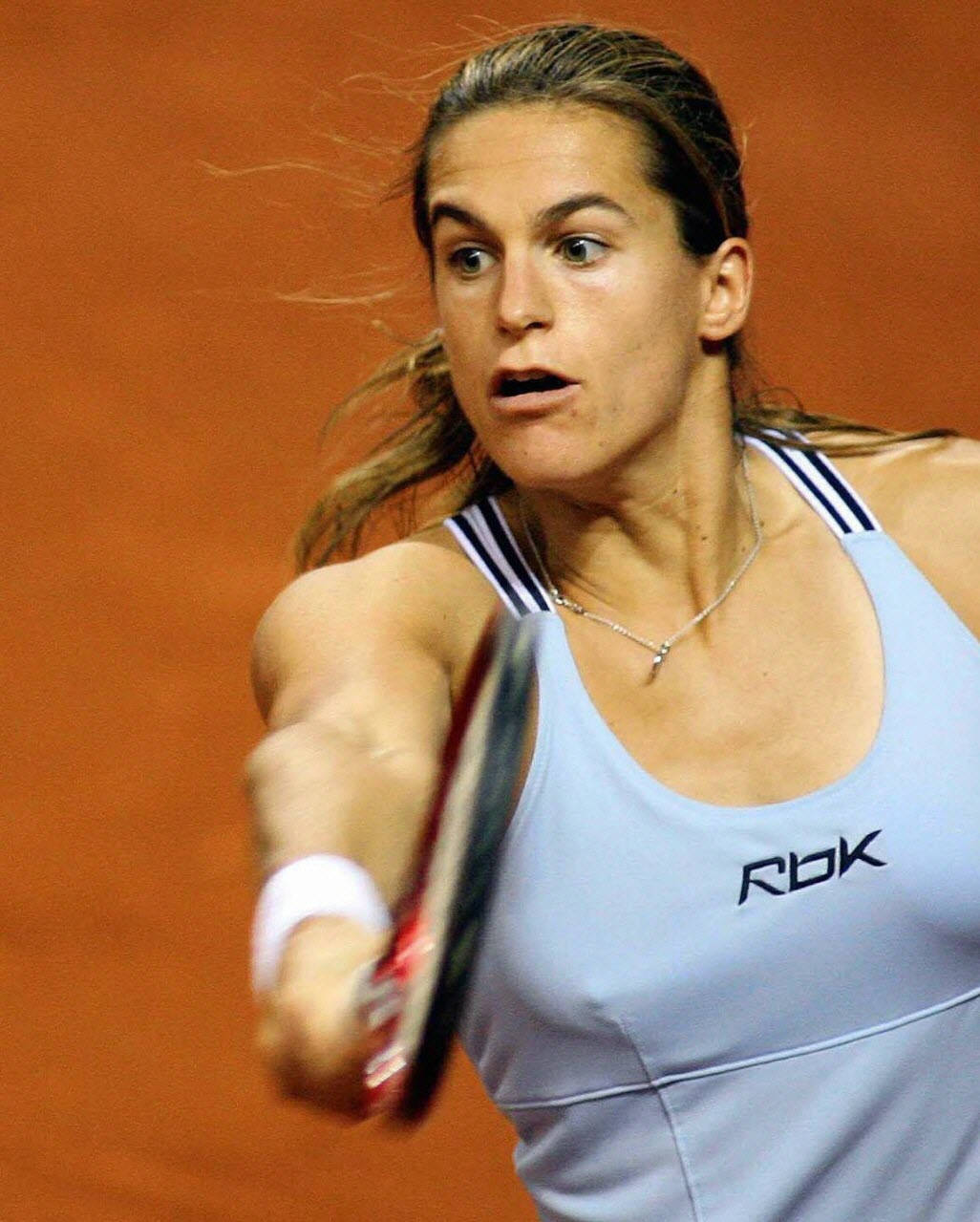 Athlete 桌布 壁紙 — 一位女網球選手在紅土球場上揮拍，專注且帶有動態模糊。