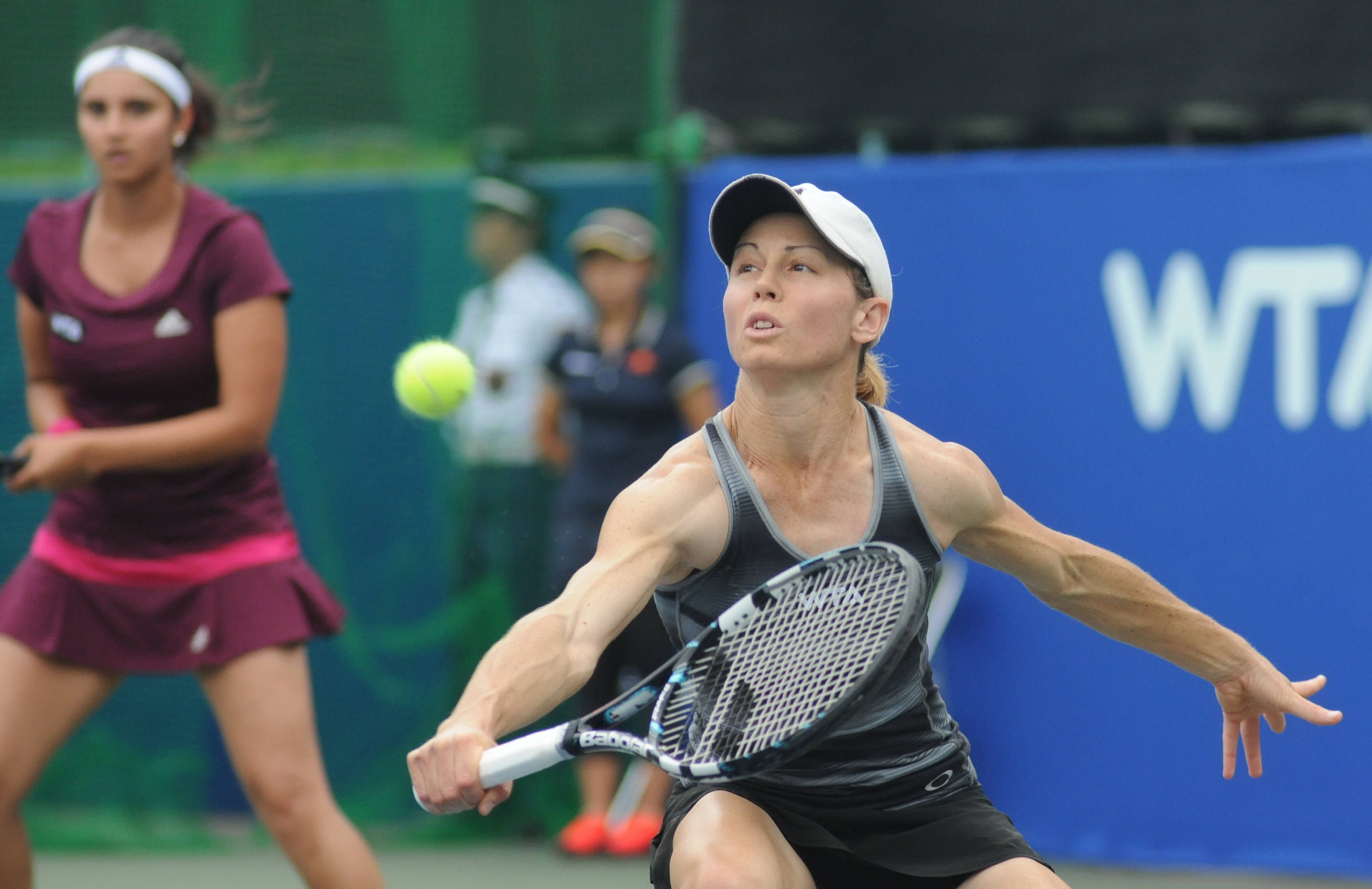 Tennis 桌布 壁紙 — 一位女網球選手在職業比賽中專注地向前撲擊一個亮黃色的球。