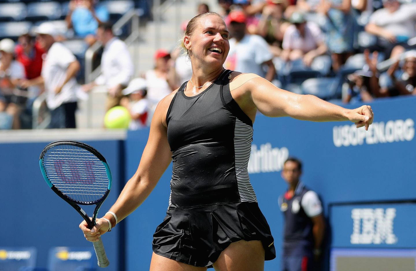 Tennis 桌布 壁紙 — 一位女網球選手在陽光普照的球場上，背景有群眾，慶祝勝利。