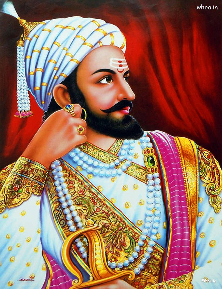 Chhatrapati Shivaji Maharaj 桌布 壁紙 — 一位威嚴的印度國王，身著華麗的藍色和金色服飾，戴著鑲有寶石的頭巾和珍珠項鍊，背景是濃郁的紅色。