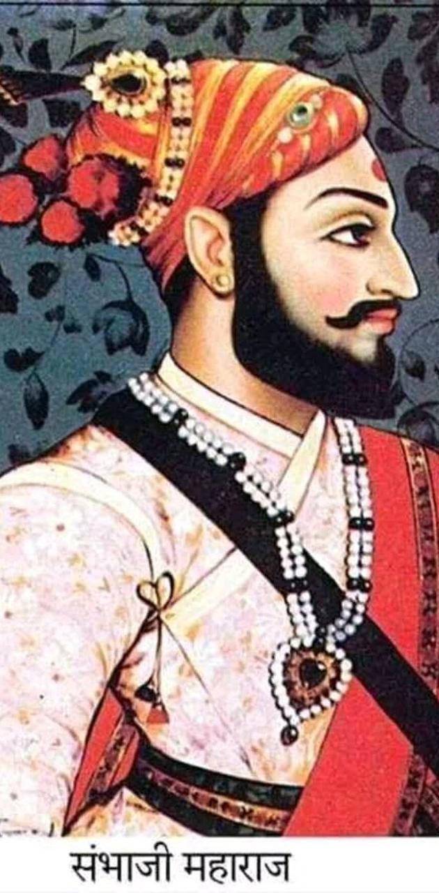 Indian 桌布 壁紙 — 一位威嚴的印度王子，戴著華麗的紅金色頭巾，飾有珠寶和珍珠，在深色花卉背景下向右凝視。
