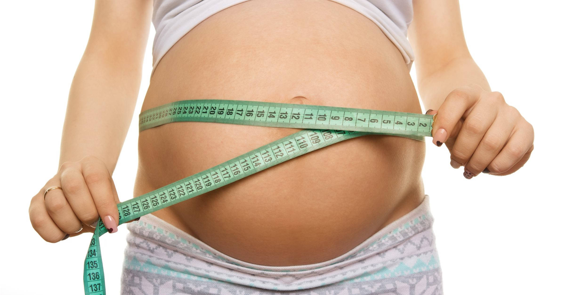 Pregnant 桌布 壁紙 — 一位孕婦在白色背景前將綠色軟尺圍在肚子上。