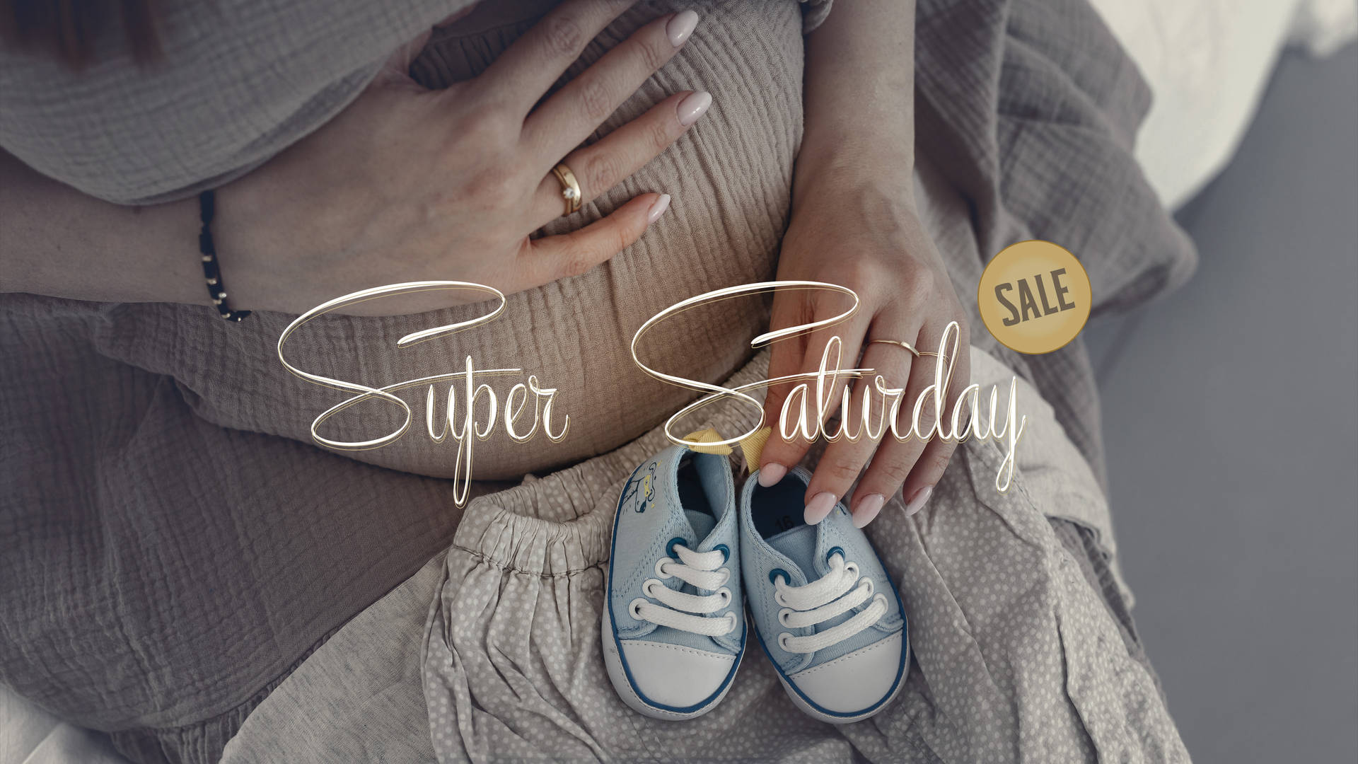 Pregnant 桌布 壁紙 — 一位孕婦用戴著戒指的雙手捧著腹部，旁邊放著嬰兒鞋，光線柔和暗淡。