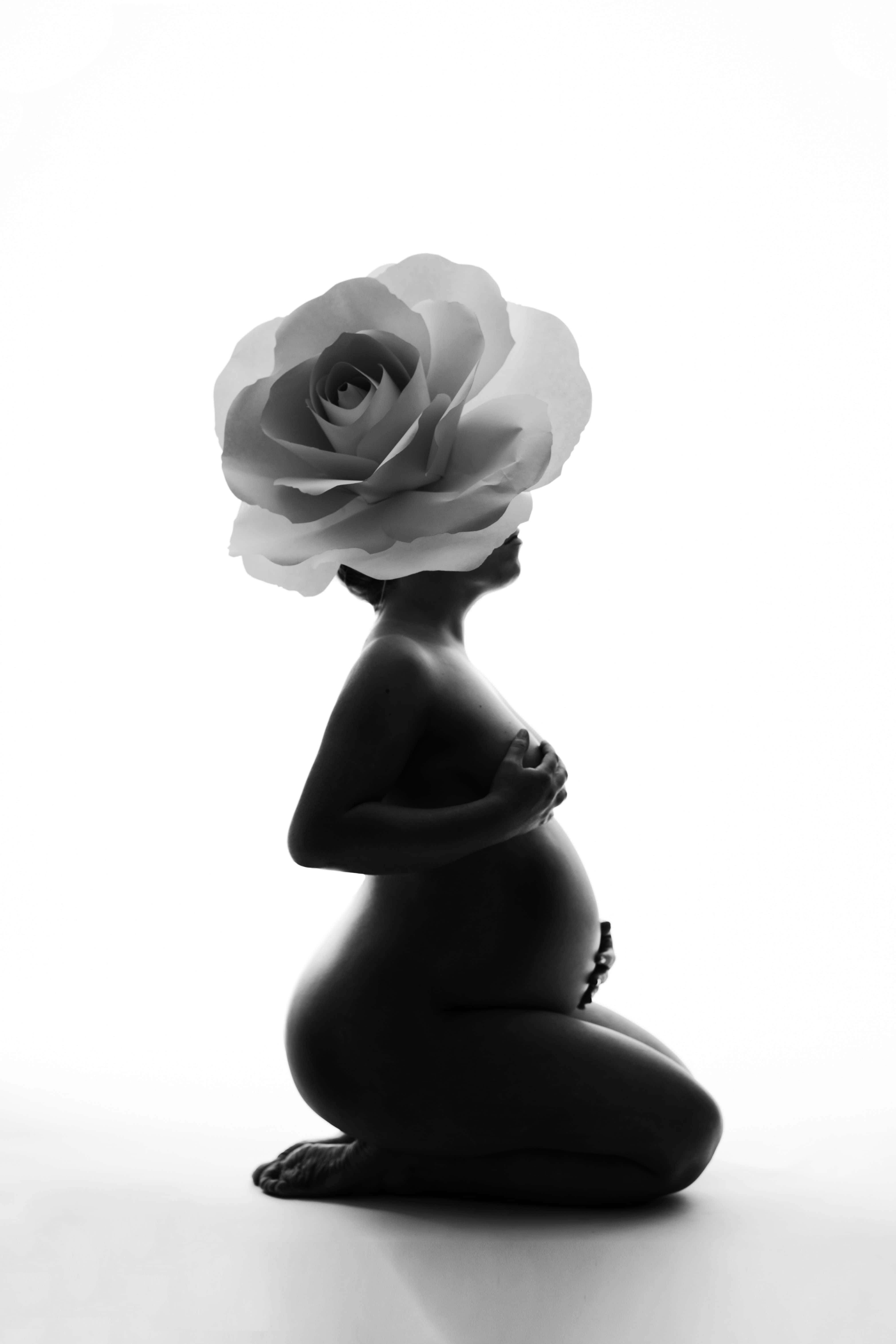Pregnant 桌布 壁紙 — 一位孕婦跪著形成剪影，一朵大玫瑰取代了她的頭部，背景是純白色。