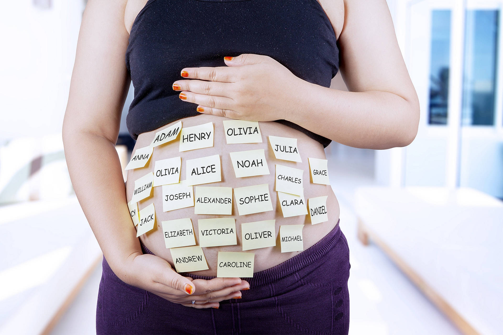 Pregnant 桌布 壁紙 — 一位孕婦輕輕地抱著她佈滿黃色便利貼的肚子，上面寫著嬰兒名字。