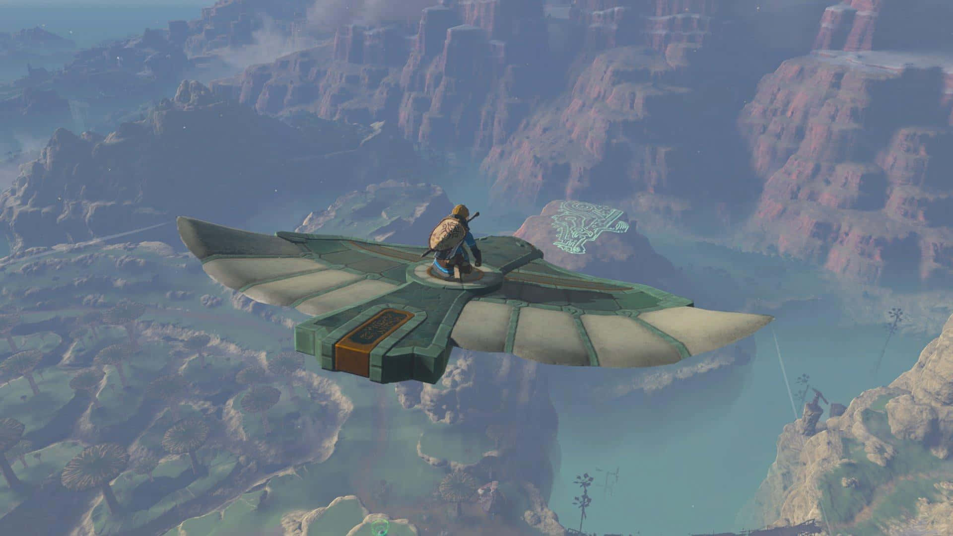 The Legend Of Zelda Tears Of The Kingdom 桌布 壁紙 — 一位孤獨的冒險家乘坐滑翔機翱翔在廣闊的峽谷景觀之上，下方是霧氣繚繞的山峰和蜿蜒的河流。
