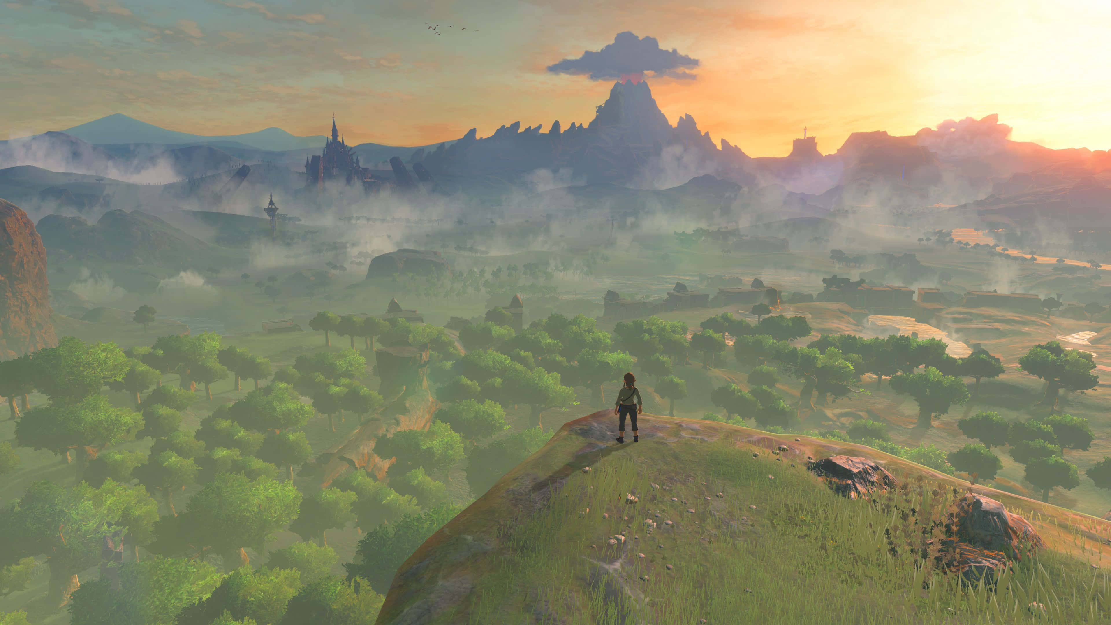 Breath Of The Wild 桌布 壁紙 — 一位孤獨的冒險家站在長滿青草的山丘上，俯瞰著霧氣瀰漫的山谷，遠處有山脈和一座城堡，天空是金色的日落。