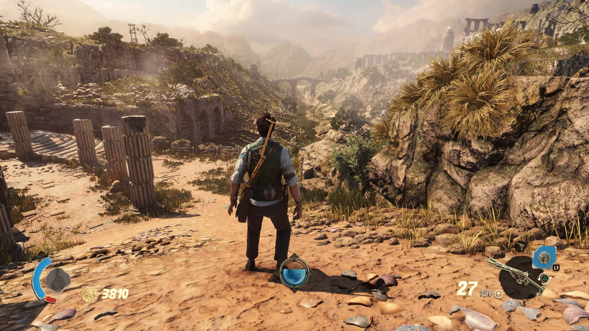 1366x768 Strange Brigade 桌布 壁紙 — 一位孤獨的冒險家站在陽光明媚的沙漠小徑上，旁邊是古老的石頭廢墟，遠山在朦朧的天空下若隱若現。