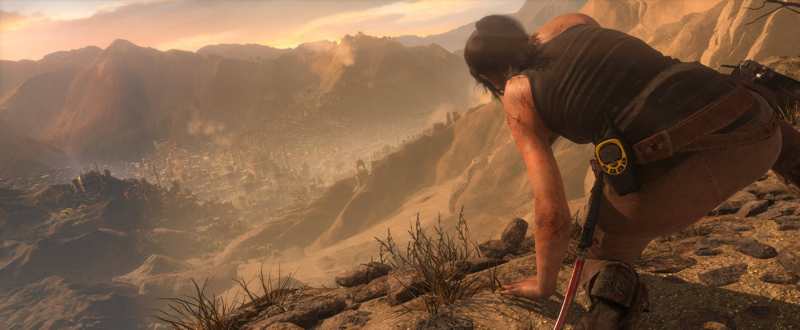 Rise Of The Tomb Raider 桌布 壁紙 — 一位孤獨的冒險家蹲在岩石懸崖上，俯瞰著沐浴在金色日落光芒中的廣闊古代廢墟山谷。