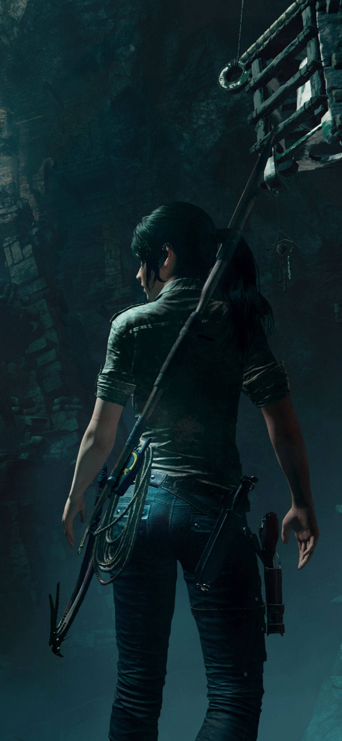 tomb raider iPhone 桌布 壁紙 — 一位孤獨的冒險者帶著抓鉤，站在光線昏暗的古代遺跡中，周圍是石牆和懸掛的金屬結構。