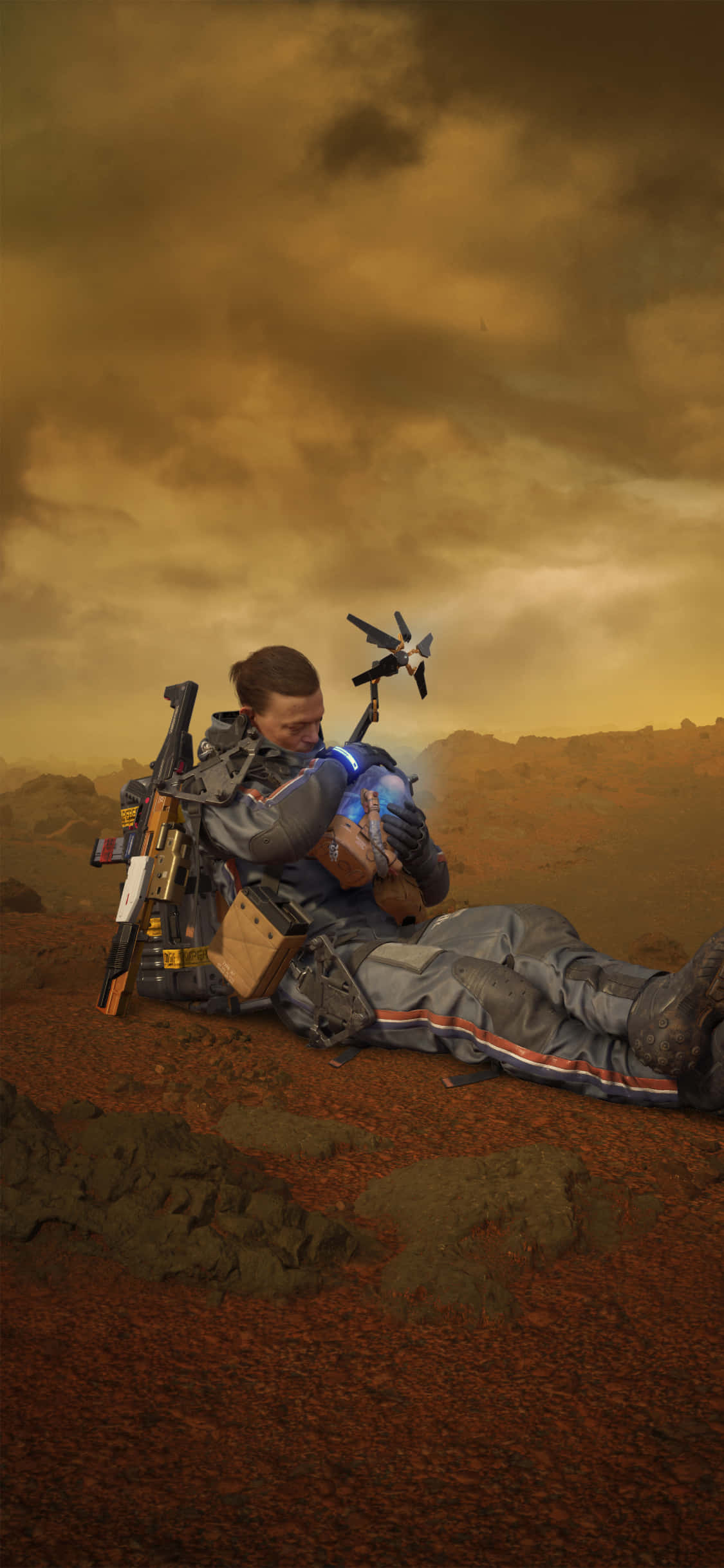 iPhone Xs Death Stranding 桌布 壁紙 — 一位孤獨的太空人在荒涼的紅色外星景觀中，在暴風雨的橙色天空下抱著一個小孩。