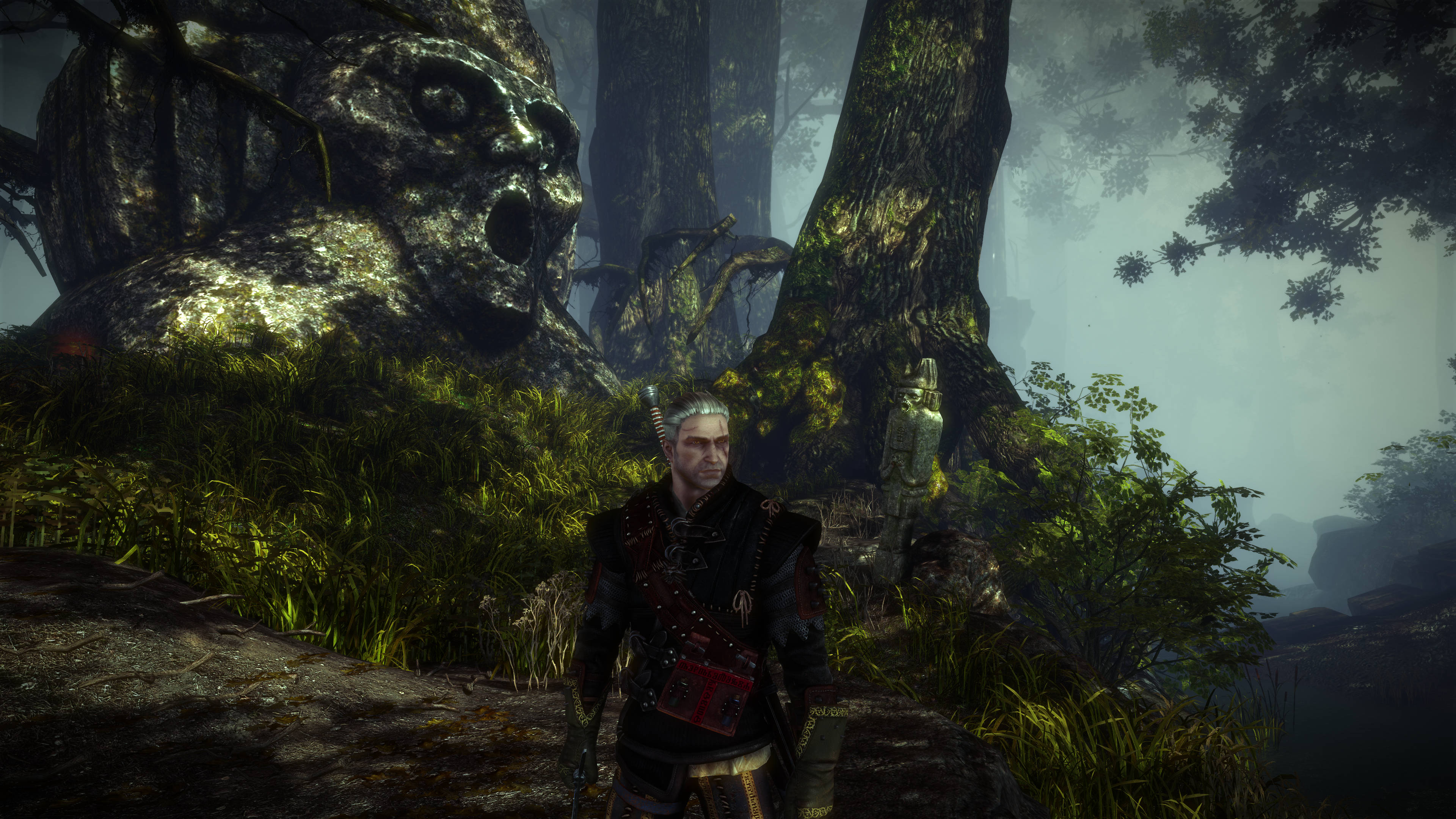 witcher 4K 桌布 壁紙 — 一位孤獨的戰士站在迷霧森林中，古老的石像和高聳的樹木投下陰影。
