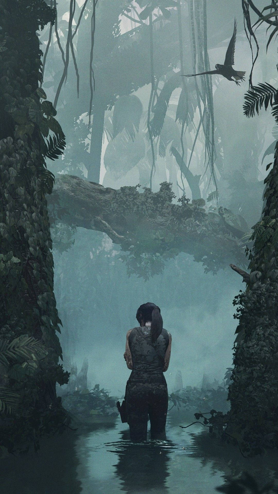 tomb raider iPhone 桌布 壁紙 — 一位孤獨的探險家涉水穿過迷霧籠罩的叢林，四周是高聳的樹木和垂掛的藤蔓，頭頂有一隻鳥在翱翔。