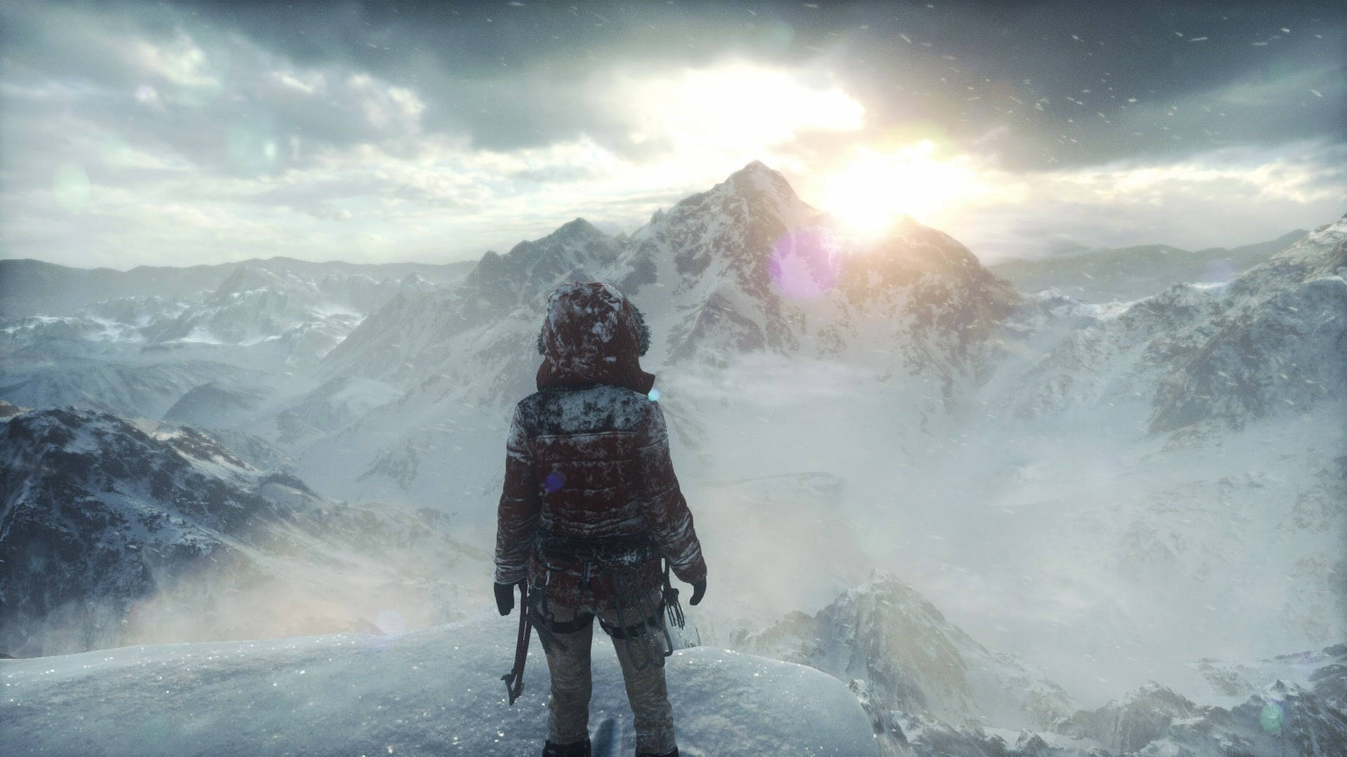Rise Of The Tomb Raider 桌布 壁紙 — 一位孤獨的探險家穿著冬季裝備，站在白雪覆蓋的山頂上，凝視著陽光照耀的地平線。