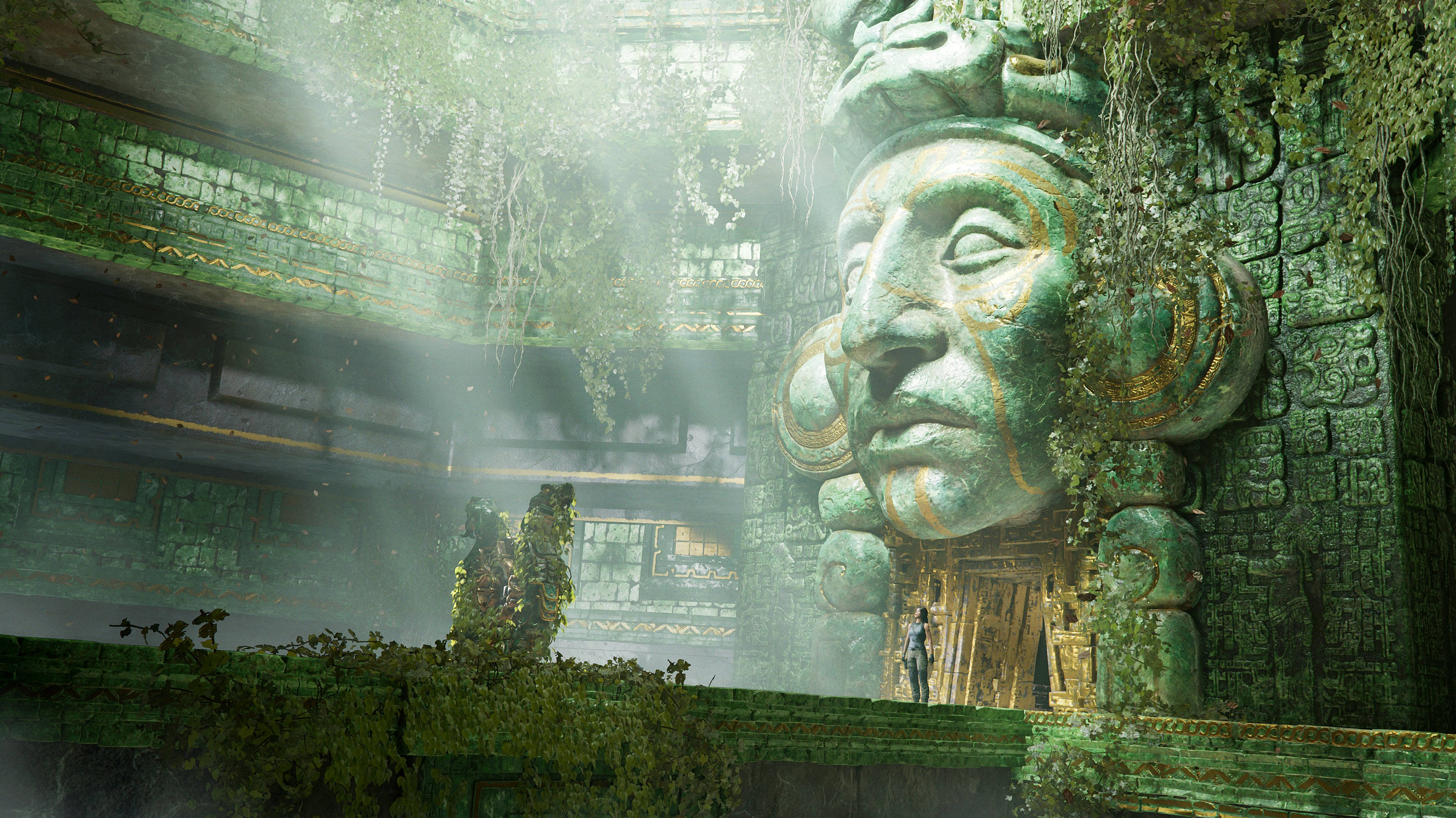 shadow 桌布 壁紙 — 一位孤獨的探險家站在霧氣瀰漫的叢林寺廟中，面對一個巨大的佈滿青苔的石頭面孔，陽光穿過樹冠灑落。