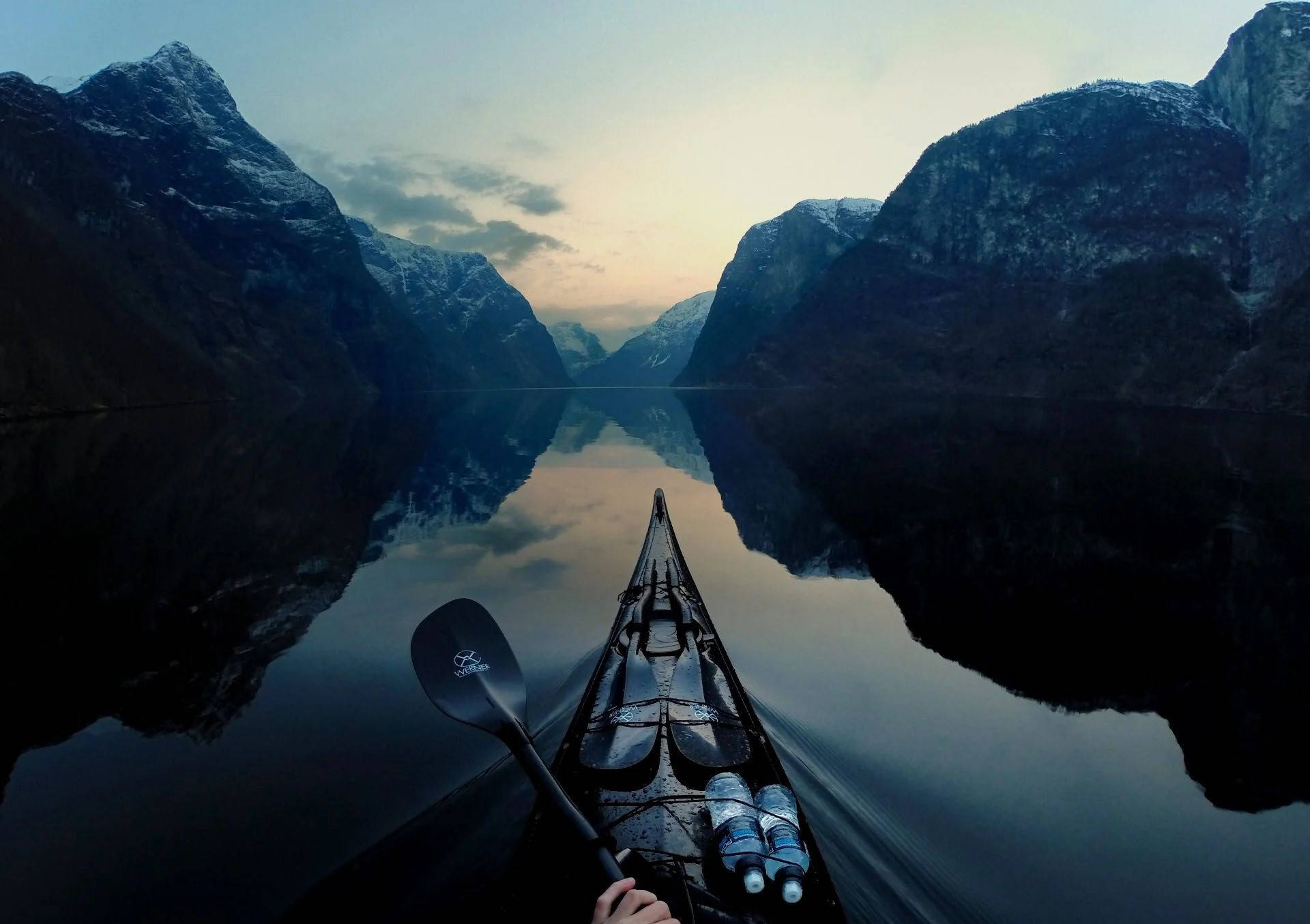 Rowing 桌布 壁紙 — 一位孤獨的皮划艇運動員在黃昏時分滑過寧靜的峽灣，積雪覆蓋的山脈倒映在平靜的水面上。