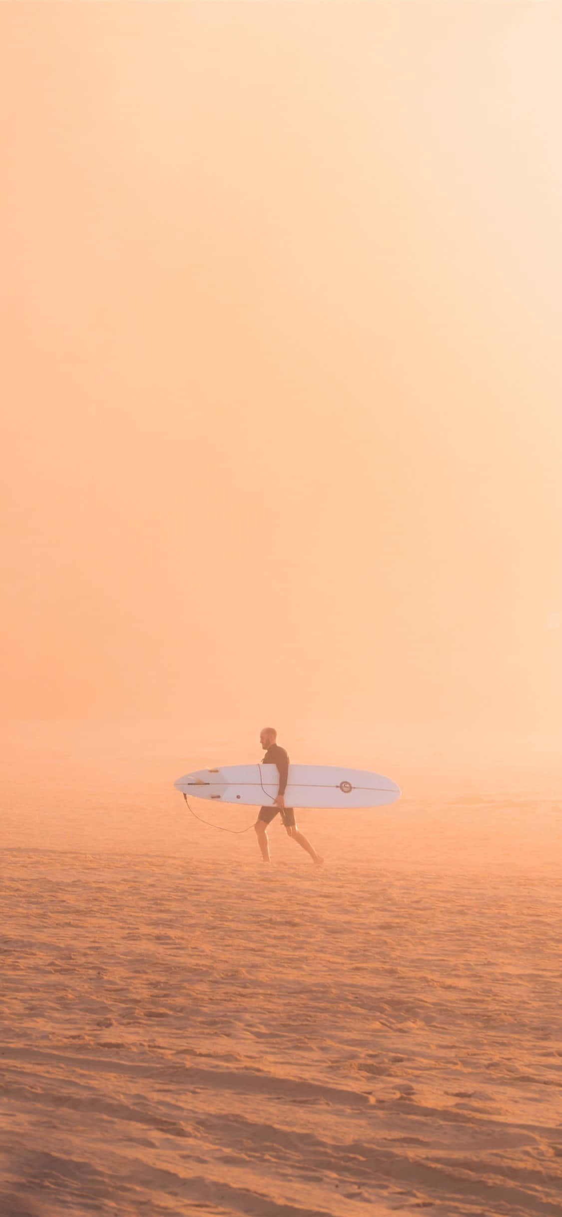 surfing 桌布 壁紙 — 一位孤獨的衝浪者在日出時分，在橙色的天空下，帶著白色衝浪板走過霧氣瀰漫的海灘。