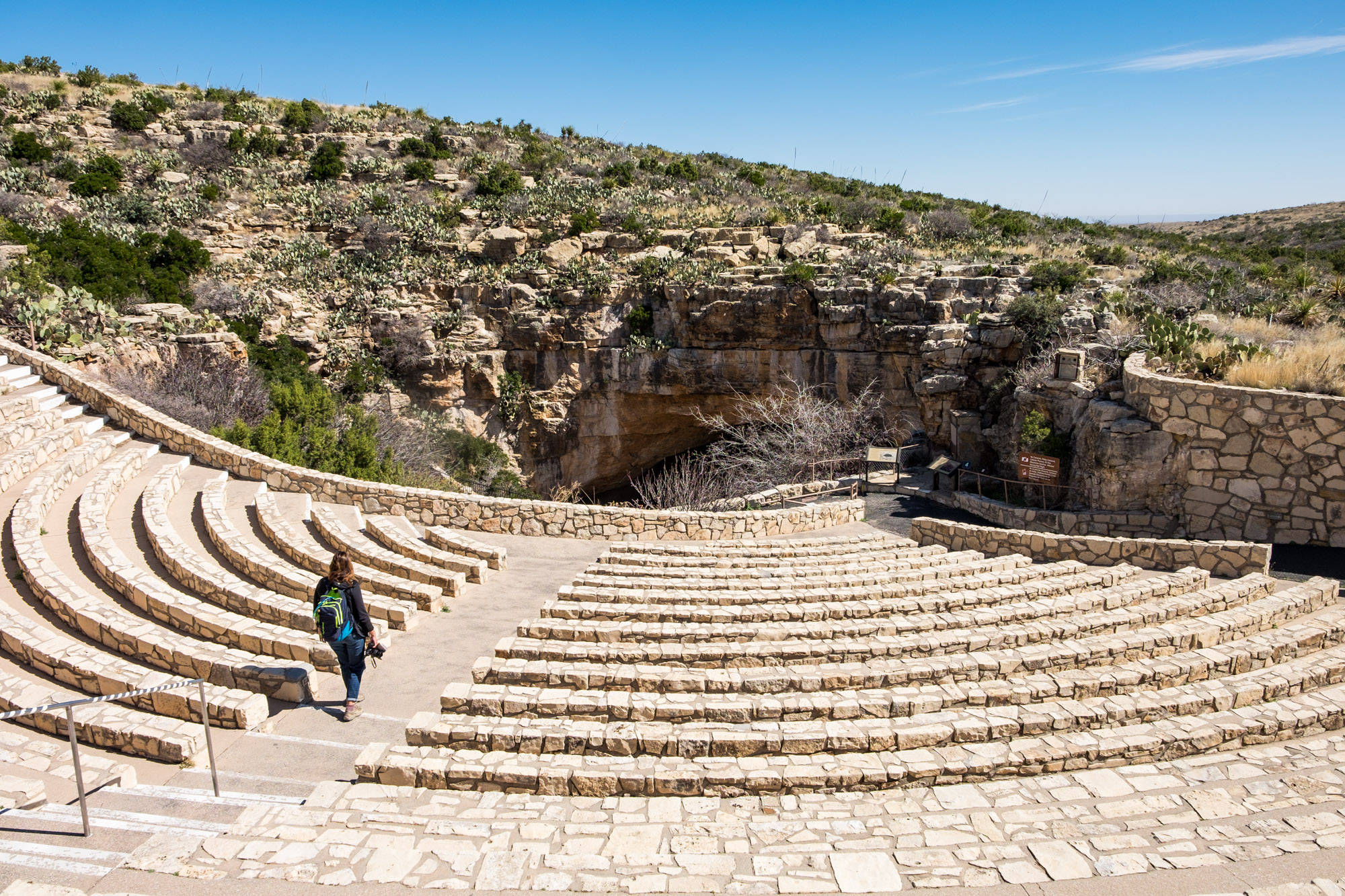 Carlsbad Caverns 桌布 壁紙 — 一位孤獨的遠足者沿著刻在陽光普照的沙漠峽谷牆壁上的古老圓形劇場的石階往下走。