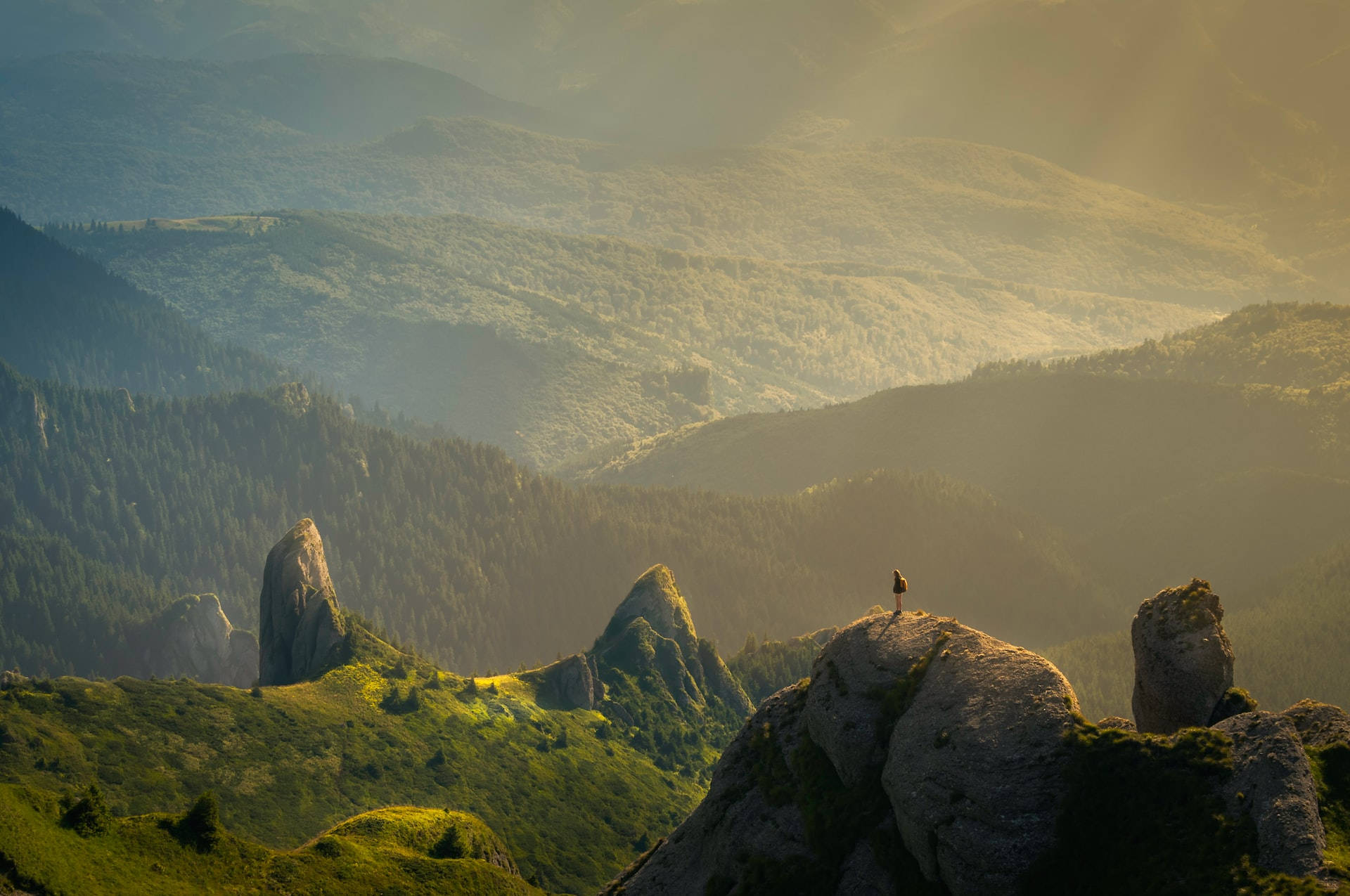 Mountain Landscape 桌布 壁紙 — 一位孤獨的遠足者站在陽光普照的岩石山頂上，俯瞰著沐浴在金色晨光中的廣闊霧氣繚繞的山谷。