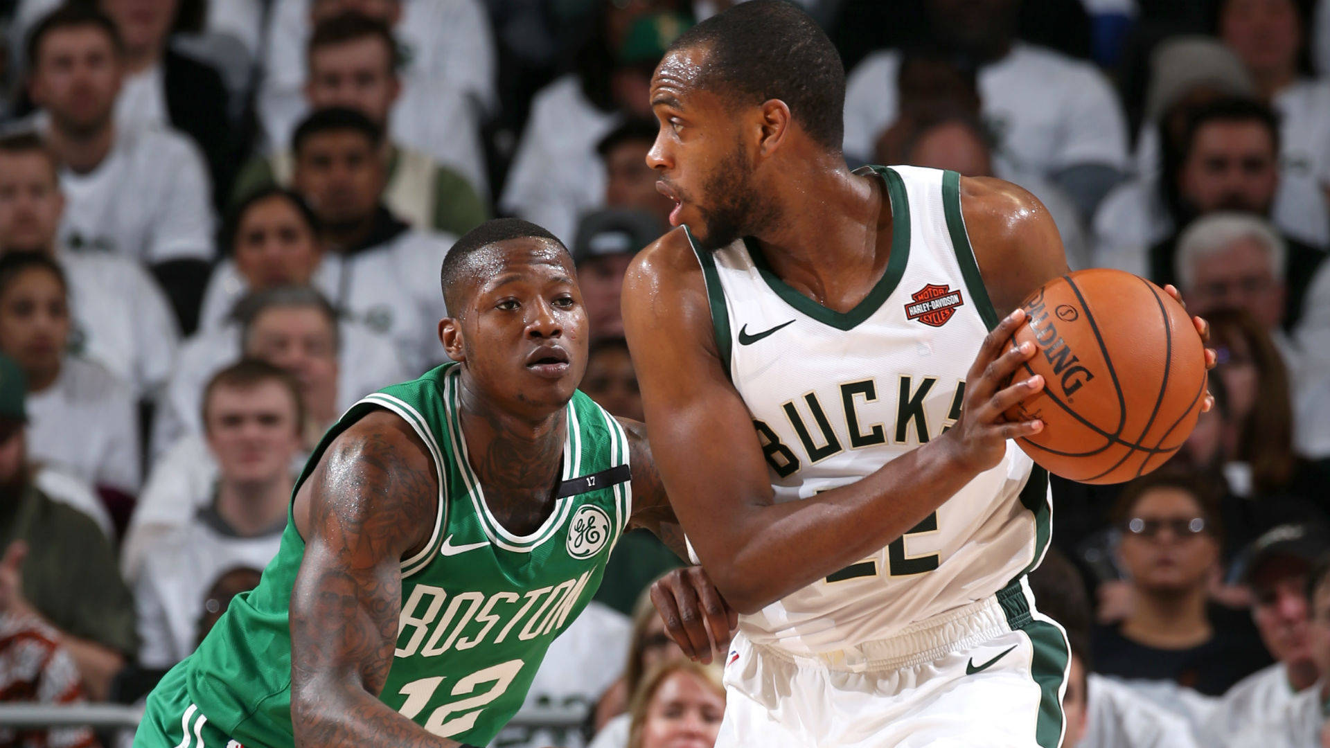 Khris Middleton 桌布 壁紙 — 一位密爾瓦基公鹿球員在明亮的場館燈光下，於一場激烈的NBA比賽中突破波士頓塞爾提克防守球員。
