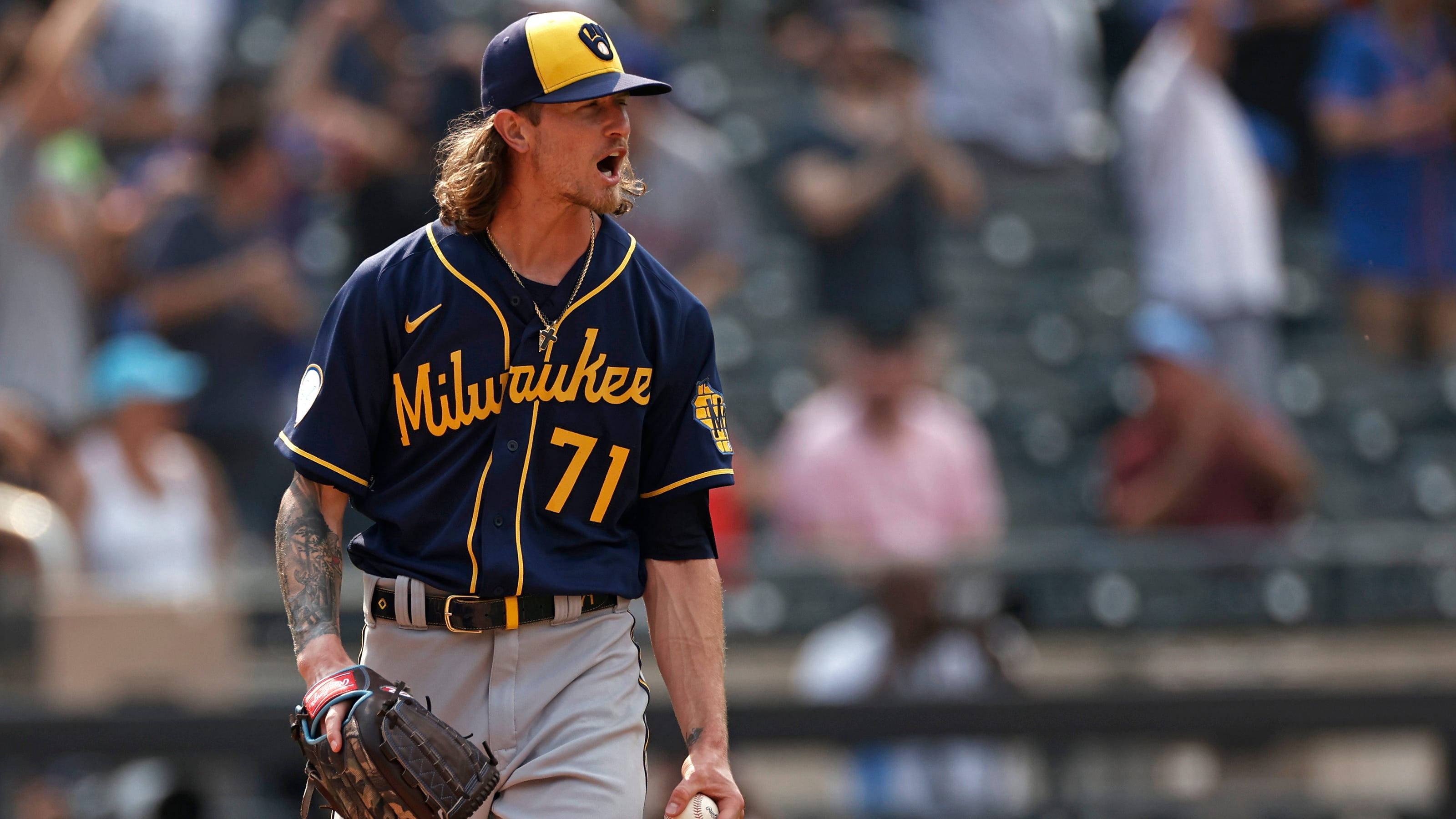 Brewers 桌布 壁紙 — 一位密爾瓦基釀酒人隊的棒球運動員，長髮且有刺青，在日間比賽中激動地大喊，手持手套和球。