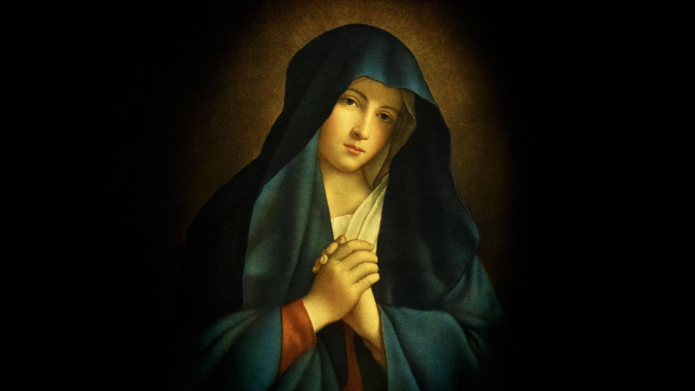 Praying 桌布 壁紙 — 一位寧靜的女子身穿深藍色面紗，在黑暗柔和的光線背景下合十祈禱。