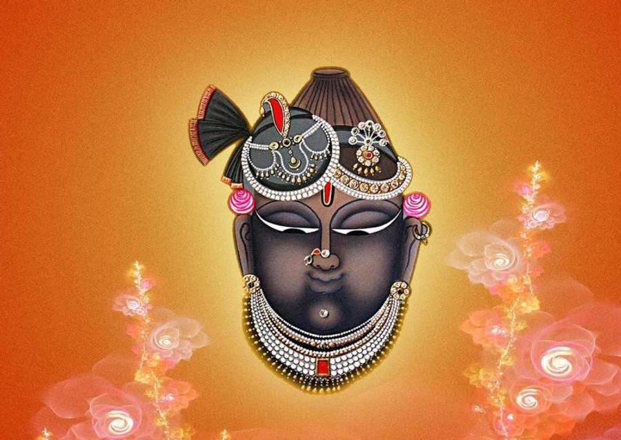 Shrinathji 桌布 壁紙 — 一位寧靜的深色皮膚神祇，閉著眼睛，飾有精緻珠寶和花卉圖案，背景是發光的橙色漸變。